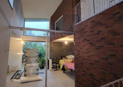 Maatwerk glazen scheidingswand in woning met dubbelhoog plafond